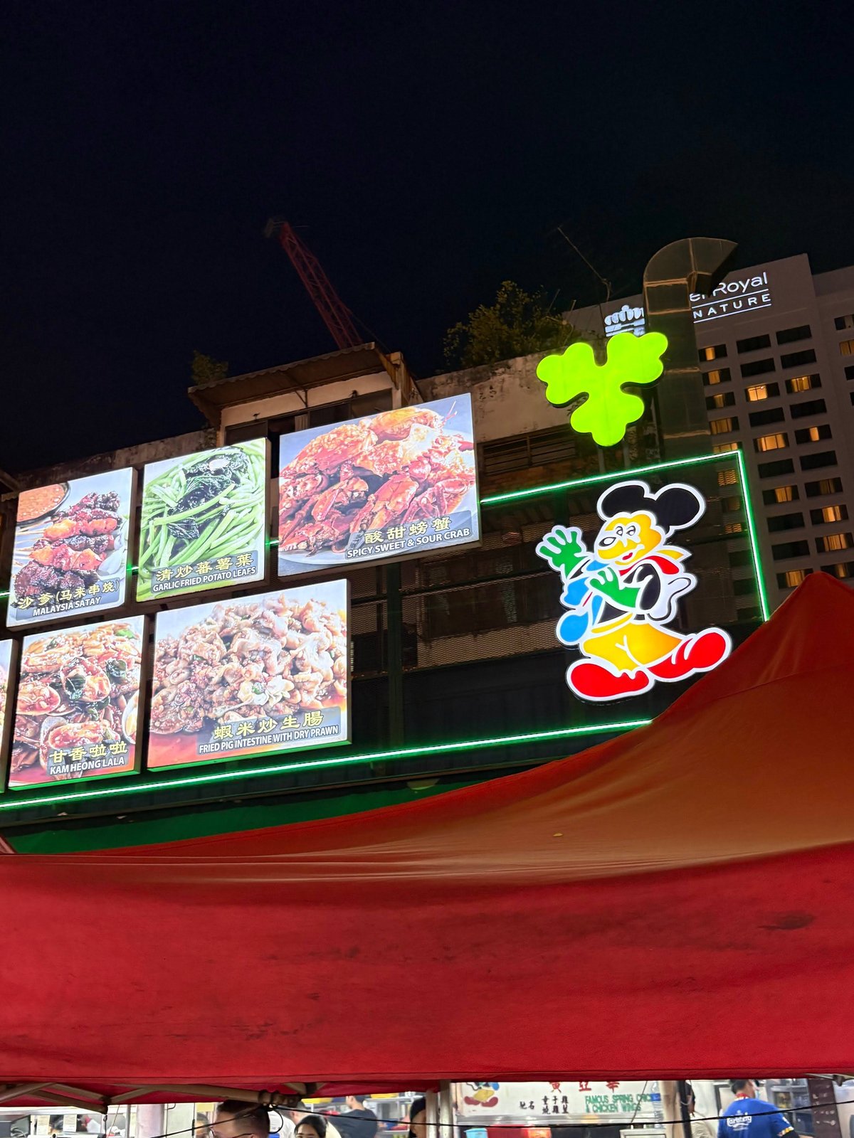 アロー通りの屋台に掲げられた、キャラクターイラスト入りの賑やかな看板