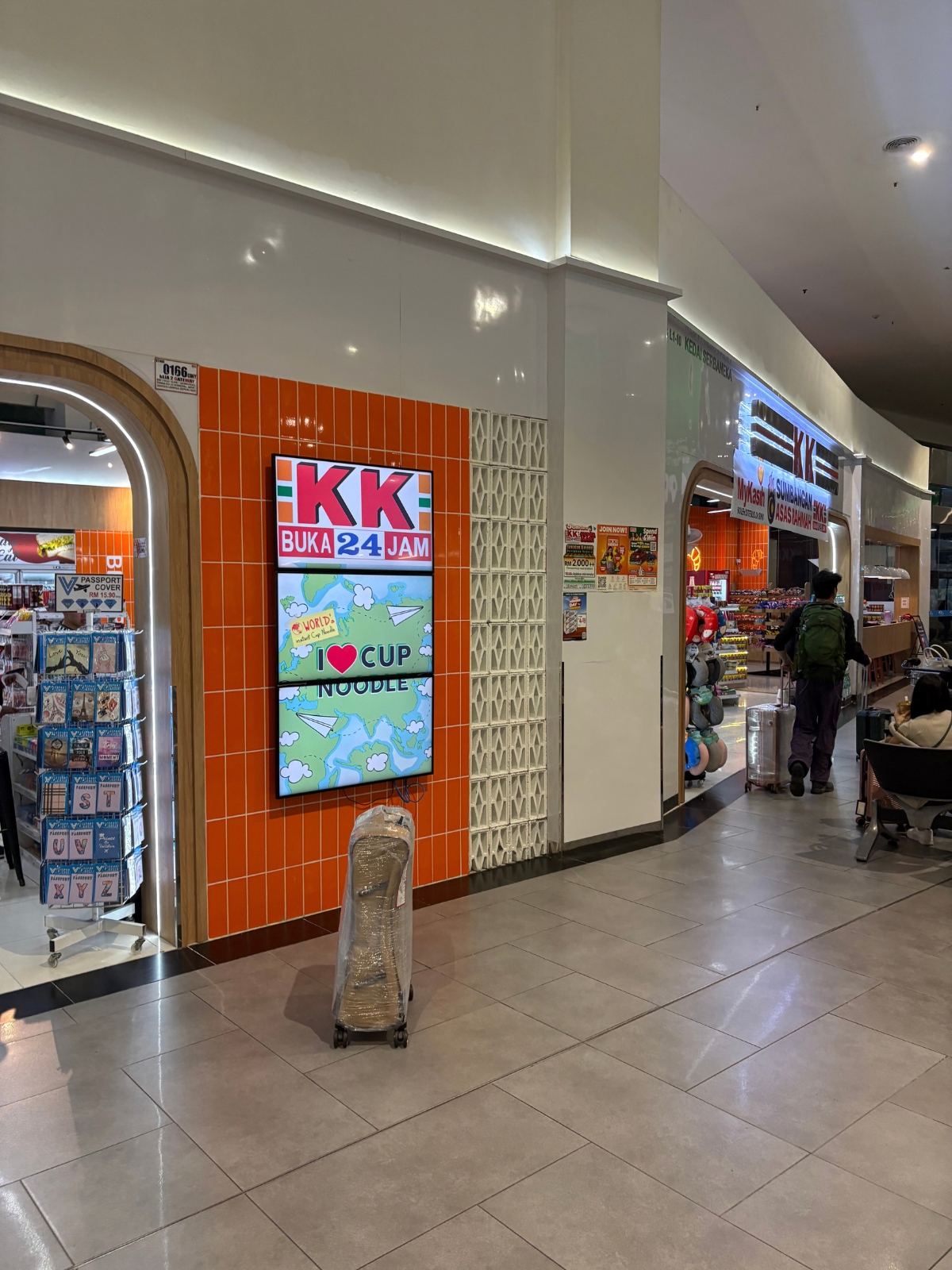 クアラルンプール国際空港内のコンビニ「KK」の入口、24時間営業を示すデジタルサイネージ