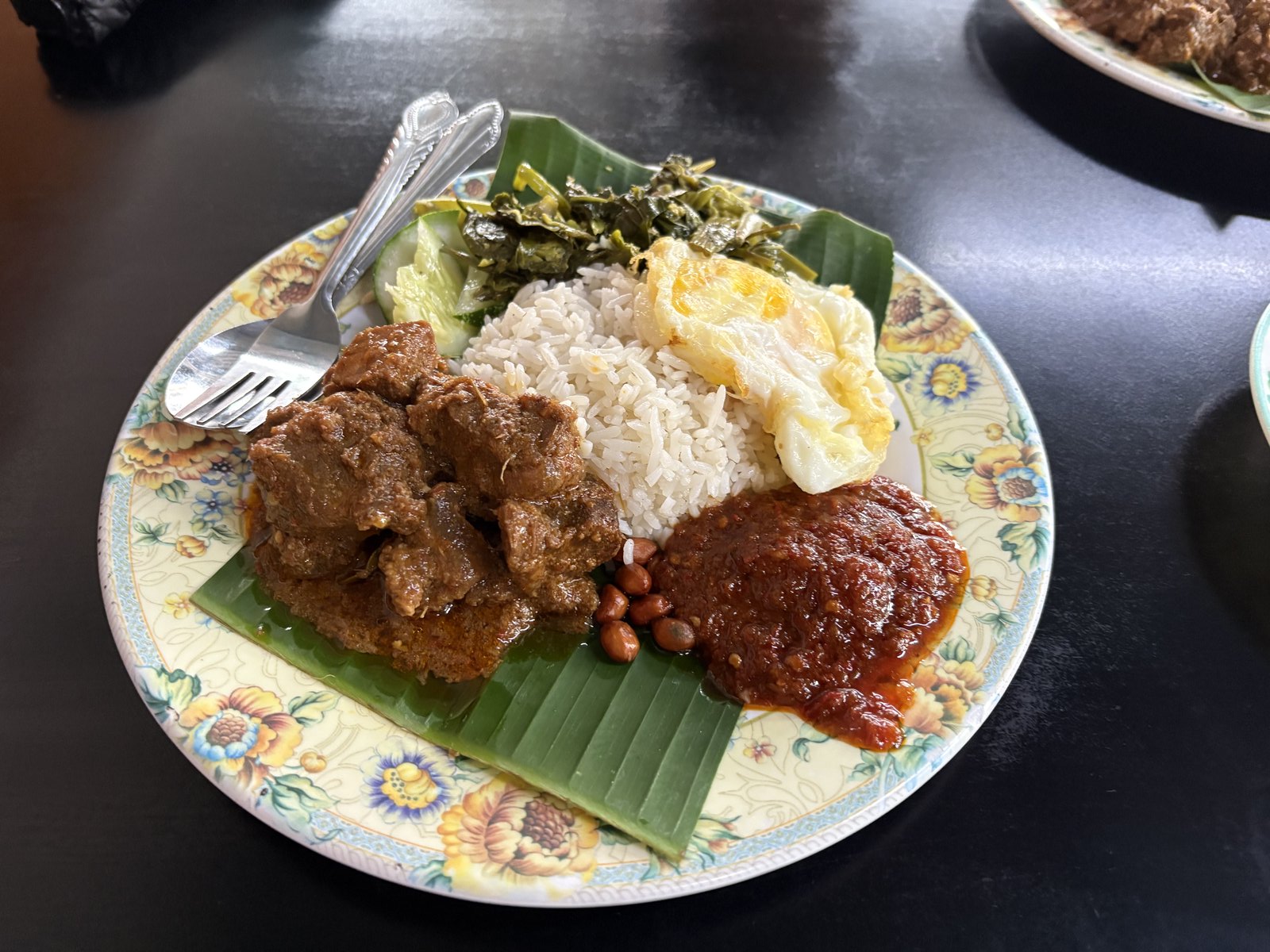 地元の安食堂でバナナリーフに盛られたナシレマ、ルンダンと目玉焼き添え