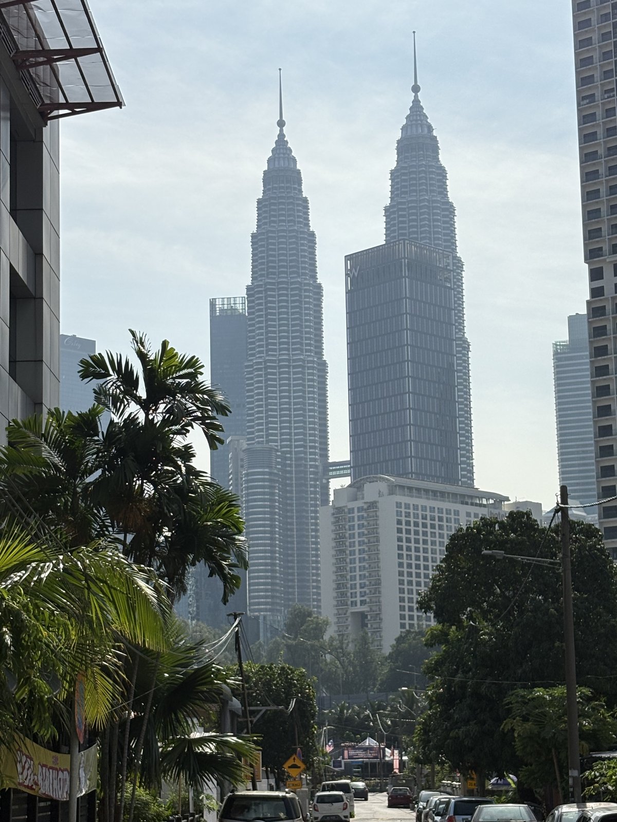 クアラルンプールの街並みの奥にそびえるペトロナスツインタワーの昼景